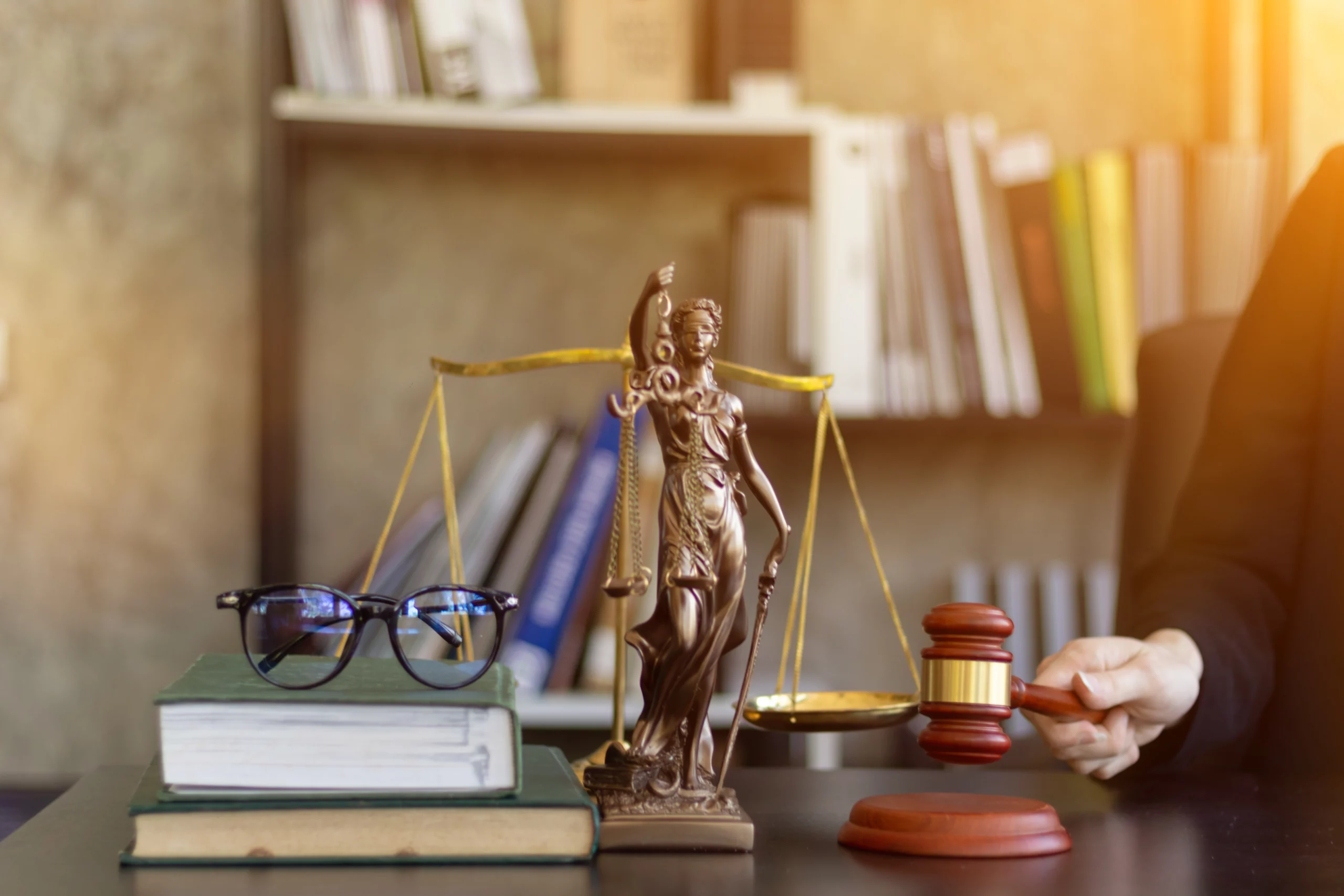 Estatueta da justiça, livros e martelo sobre a secretária de um advogado